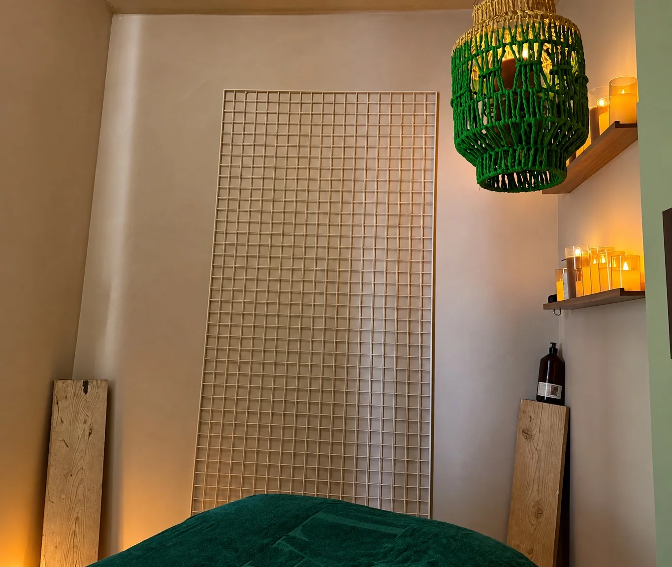 Cabine NEXT : claustra mural, bougies et suspension tressée verte au-dessus de la table