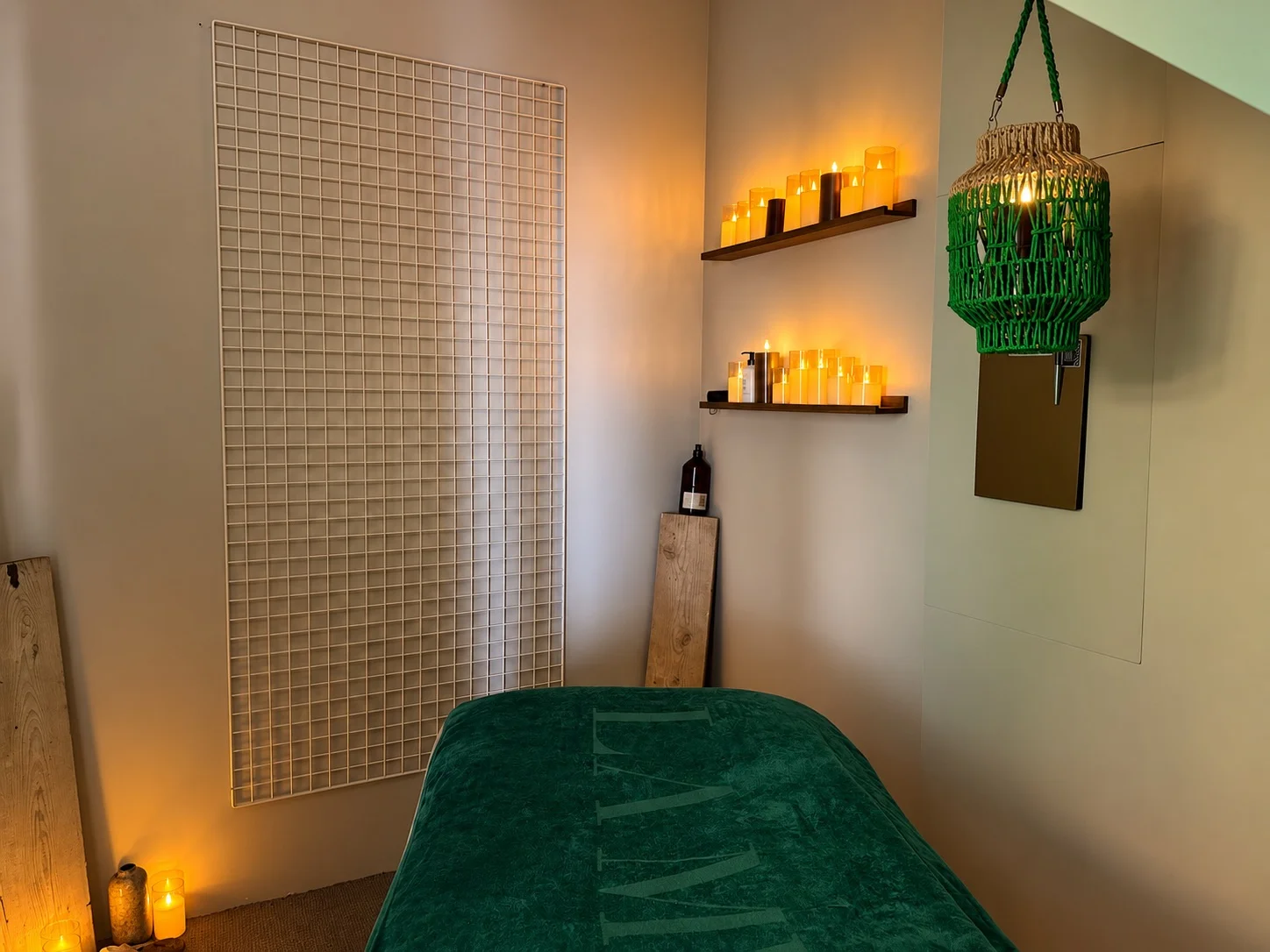 Table de massage avec couverture verte NEXT, claustra et étagères de bougies