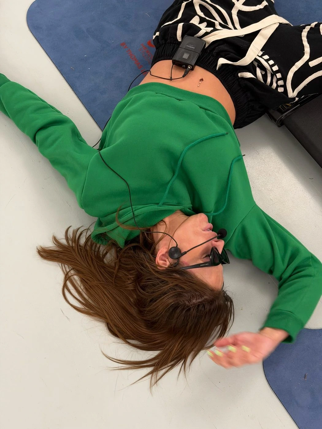 Charlotte en tenue verte allongée près d’un tapis bleu chez NEXT