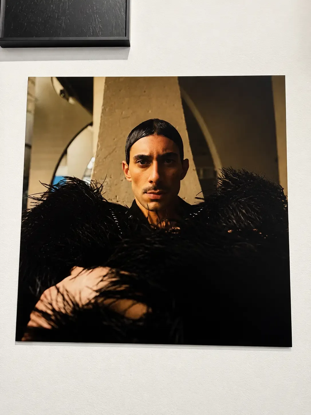 Portrait encadré d’une personne vêtue de noir dans la galerie NEXT